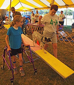 Young girl with walker, adult, dog on teeter board