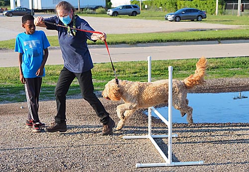 Dog flying over hurdle with 4-h'er and leader