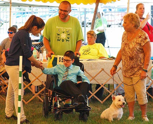 Young man in wheelchair, three adults, little white dog