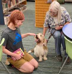 Leader, girl reading to dog in Book Hounds program